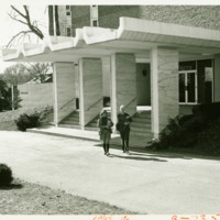 Two students walk out of Prosser Hall, ca. 1960s.