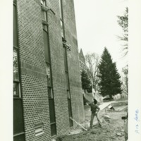 A student throws what appears to be a pillow out a window of Prosser Hall, ca. 1970.